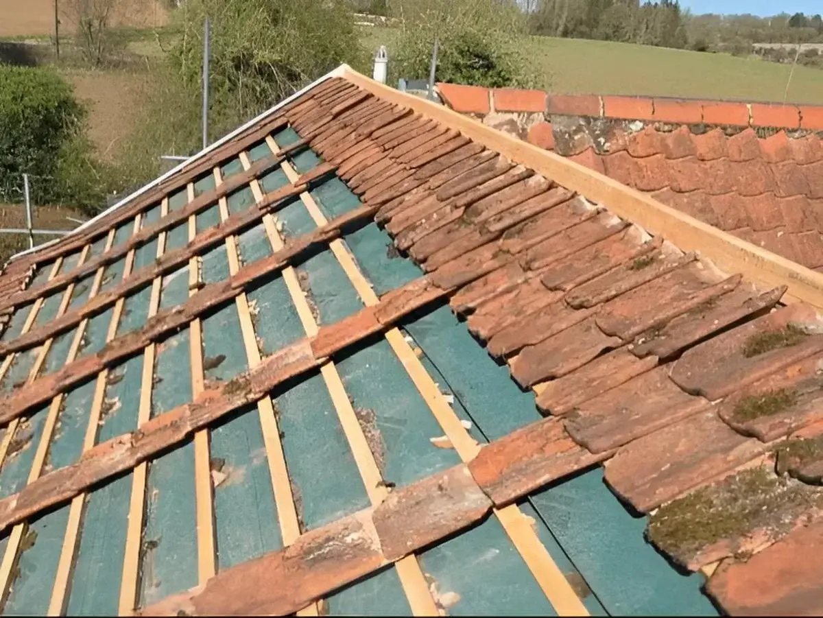Progress shot showing old clay tiles removed, revealing timber battens and a vapour-permeable underlay system during a re-roof